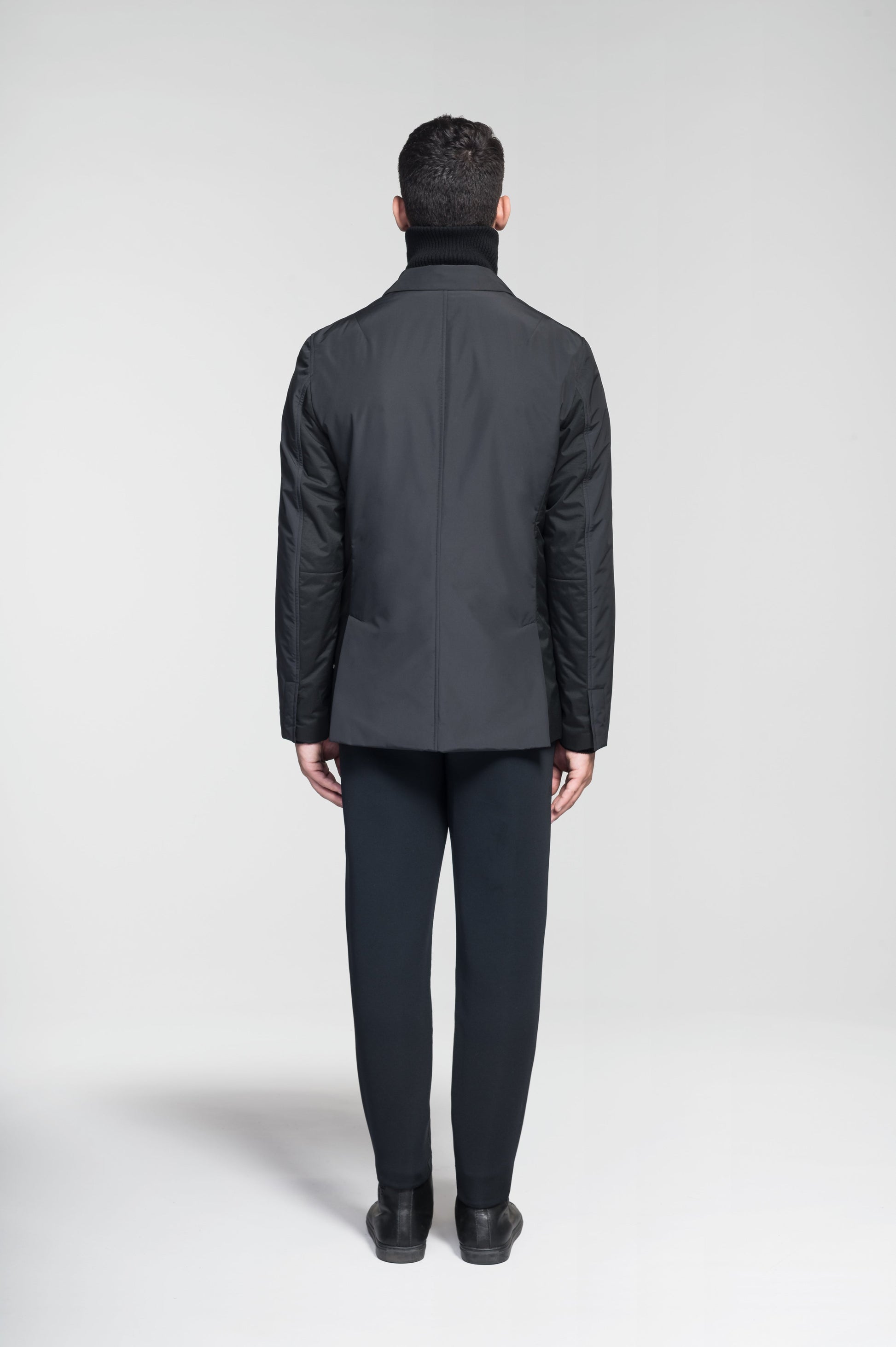 Cody Men's Tailored Travel Blazer in 3-ply micro denier and stretch nylon fabrication with DWR coating, Primaloft Gold Insulation Active+, hidden two-way zipper at centre front with snap closure placket, three invisible exterior zipper pockets, double back pleats, and hidden snap placket at cuffs, in Black