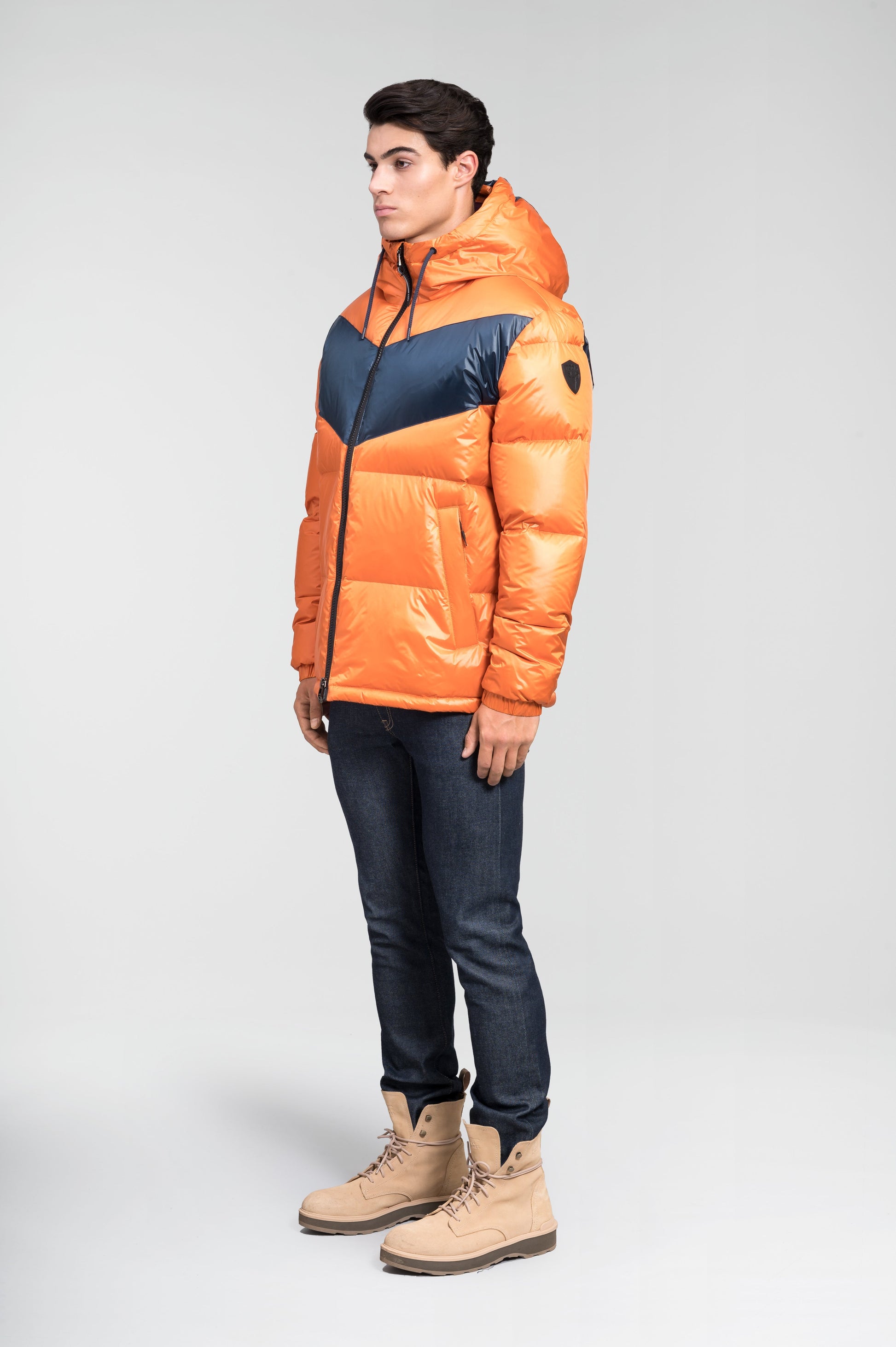 Dyna Men's Chevron Quilted Puffer Jacket in hip length, premium cire technical nylon taffeta fabrication, Premium Canadian origin White Duck Down insulation, non-removable down-filled hood, two-way centre-front zipper, fleece-lined zipper pockets at waist, pit zipper vents, in Burnt Orange