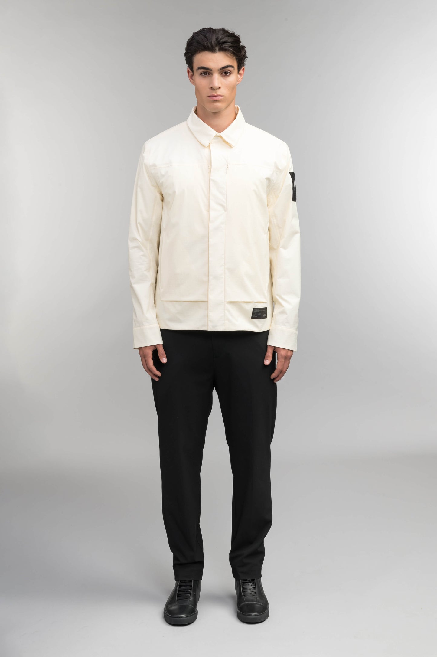 Farson Men's Waterproof Overshirt in Wheat made from premium recycled polyester ripstop with a DWR coating. Features a concealed snap-button front placket, adjustable snap cuffs, invisible chest zip pocket, dual zippered waist pockets, pit zip ventilation, and seam-sealed construction for enhanced weather protection. Designed in Canada.