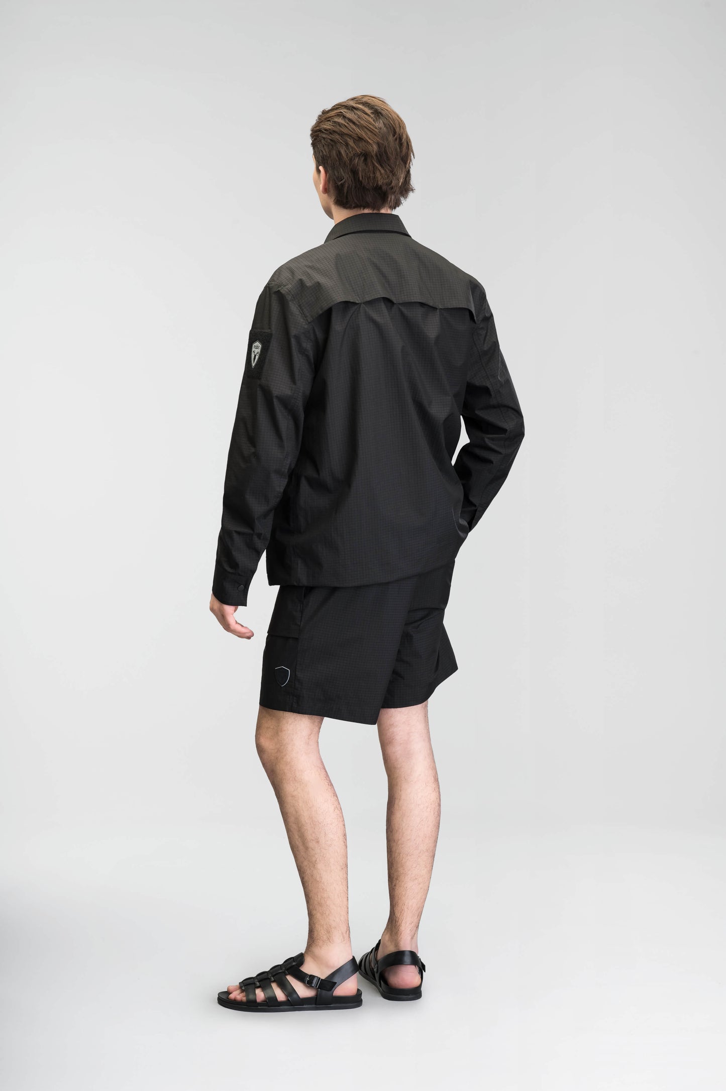 Farson Men's Waterproof Overshirt in Black made from premium recycled polyester ripstop with a DWR coating. Features a concealed snap-button front placket, adjustable snap cuffs, invisible chest zip pocket, dual zippered waist pockets, pit zip ventilation, and seam-sealed construction for enhanced weather protection. Designed in Canada.