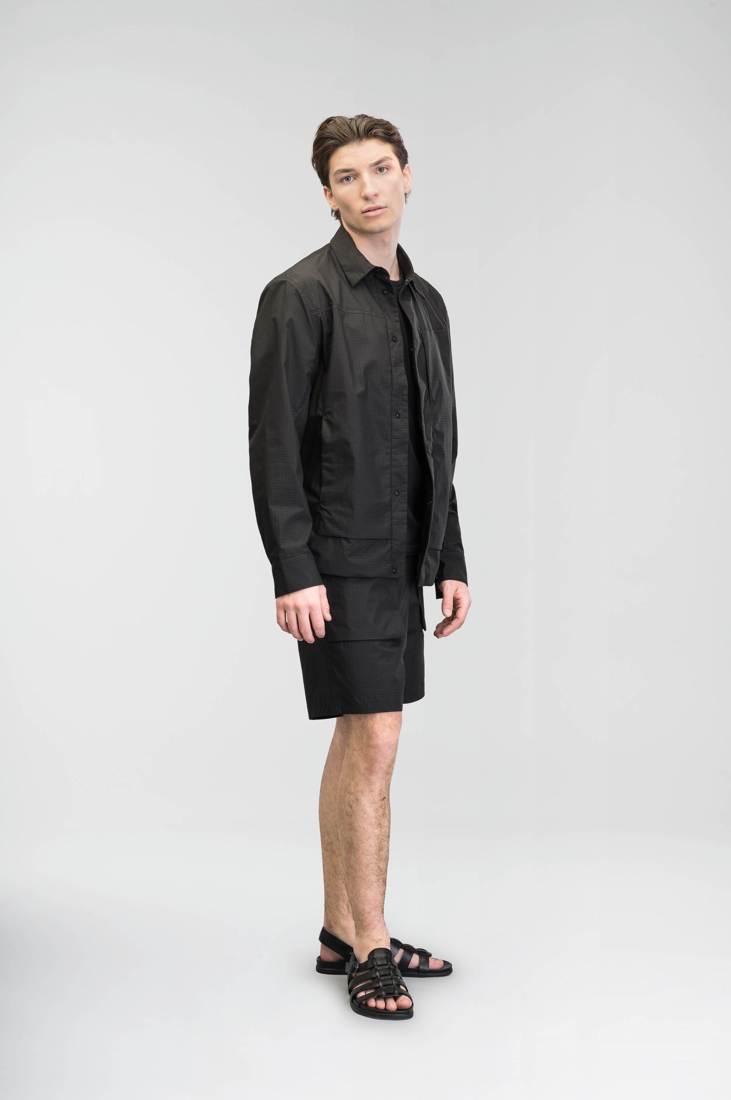 Farson Men's Waterproof Overshirt in Black made from premium recycled polyester ripstop with a DWR coating. Features a concealed snap-button front placket, adjustable snap cuffs, invisible chest zip pocket, dual zippered waist pockets, pit zip ventilation, and seam-sealed construction for enhanced weather protection. Designed in Canada.