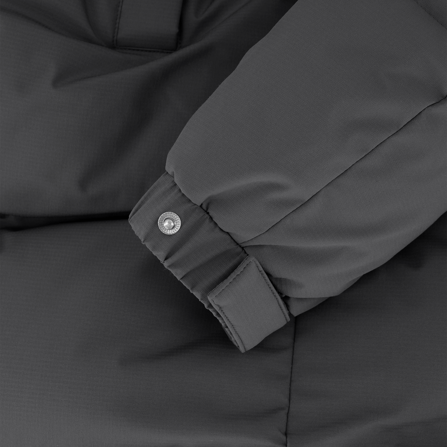 Granger long jacket in Black stretch ripstop fabric with DWR coating, insulated with Canadian white duck down and Primaloft. Features a two-way zipper, magnetic closure, and adjustable cuffs for warmth and weather protection.