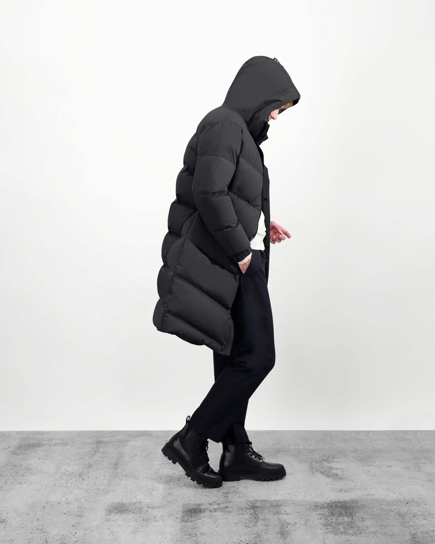 Granger long jacket in Black stretch ripstop fabric with DWR coating, insulated with Canadian white duck down and Primaloft. Features a two-way zipper, magnetic closure, and adjustable cuffs for warmth and weather protection.