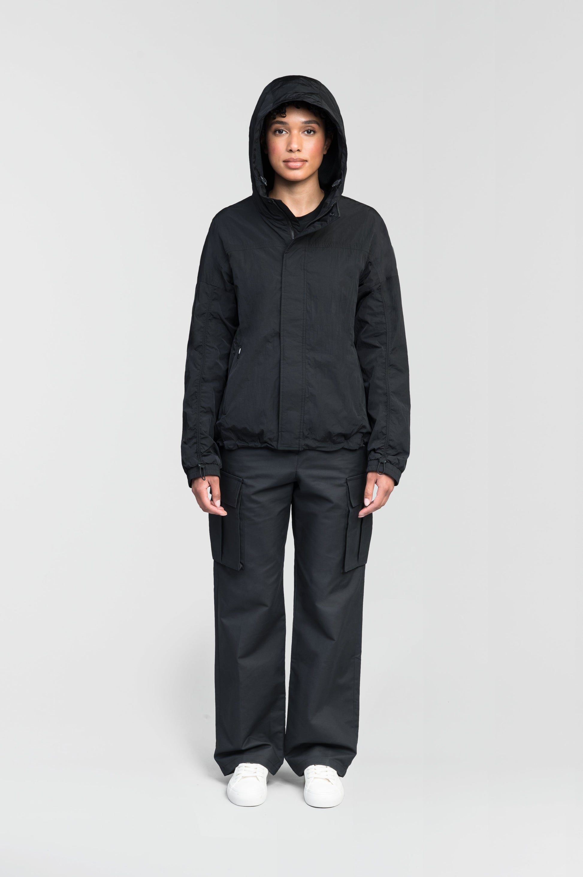 Hartley Women's Tailored Rain Jacket in hip length, two-way centre front zipper with wind flap, toggle adjustable cuffs and waist cord, non-removable hood, side entry waist pockets, in Black