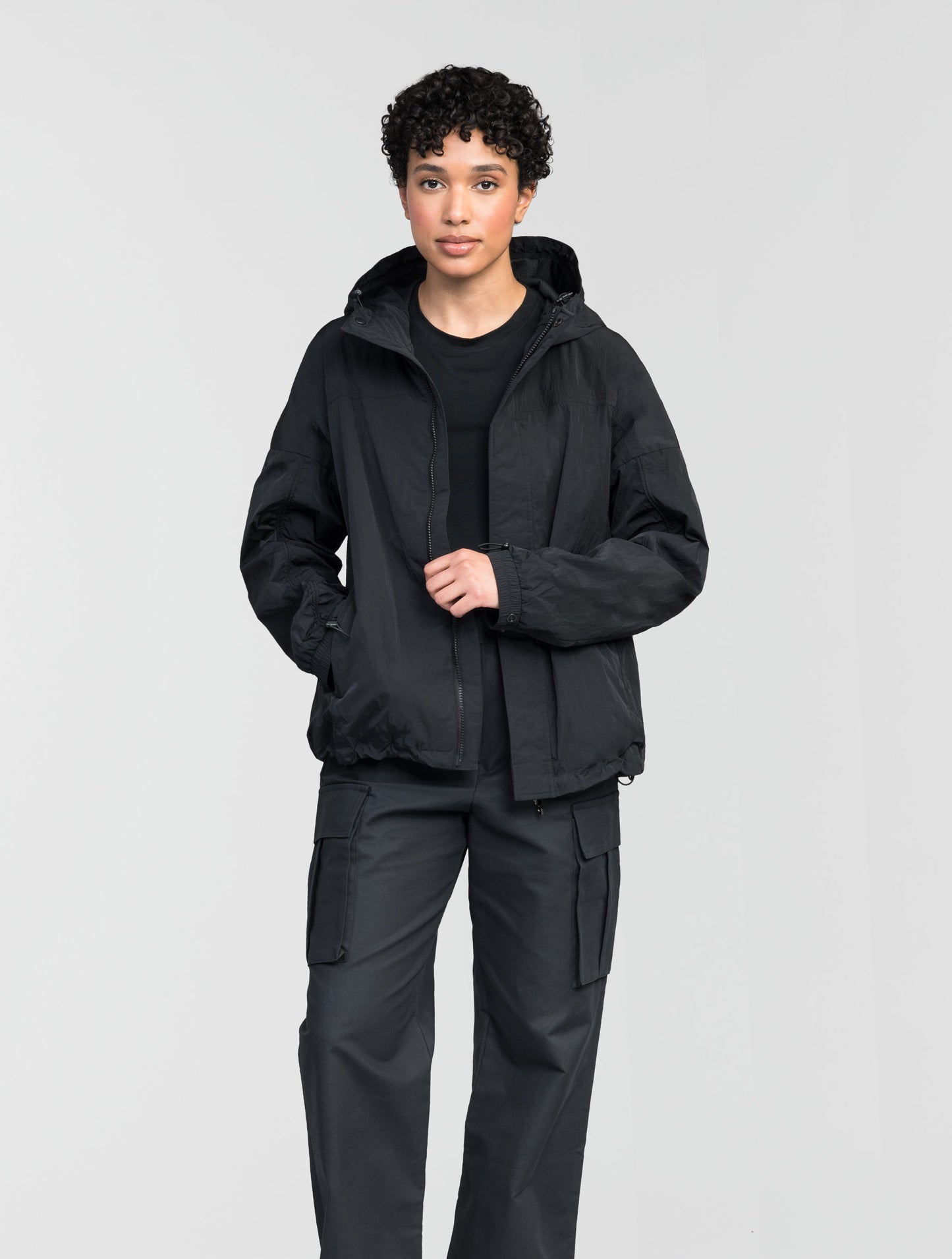 Hartley Women's Tailored Rain Jacket in hip length, two-way centre front zipper with wind flap, toggle adjustable cuffs and waist cord, non-removable hood, side entry waist pockets, in Black