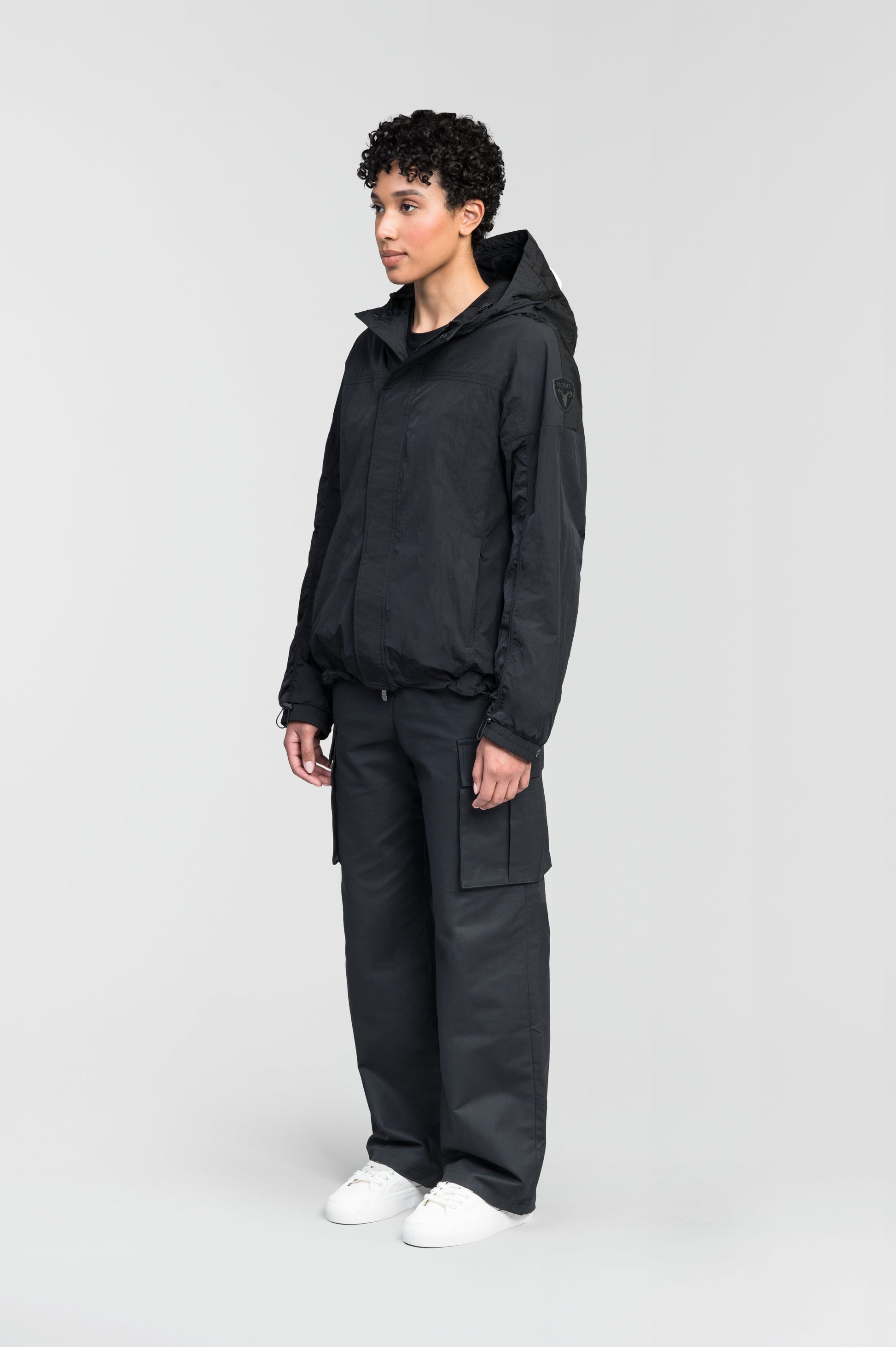 Hartley Women's Tailored Rain Jacket in hip length, two-way centre front zipper with wind flap, toggle adjustable cuffs and waist cord, non-removable hood, side entry waist pockets, in Black