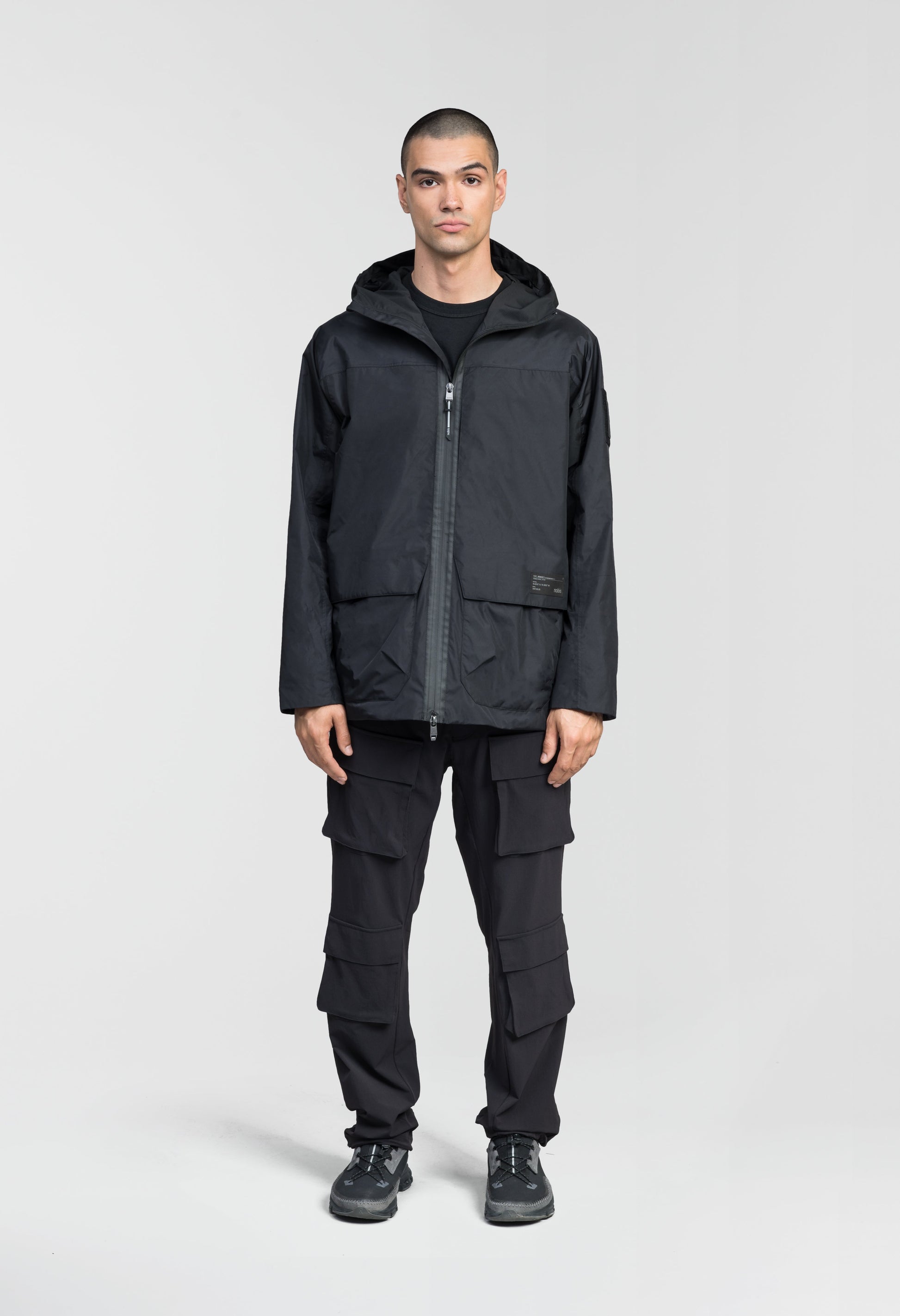 Mission Men's Performance Rain Shell Jacket in hip length, non-removable hood with adjustable toggle, two-way waterproof zipper, flap closure waist pockets with additional side entry storage, zipper ventilation on back, passive underarm ventilation, and breathable mesh lining, in Black