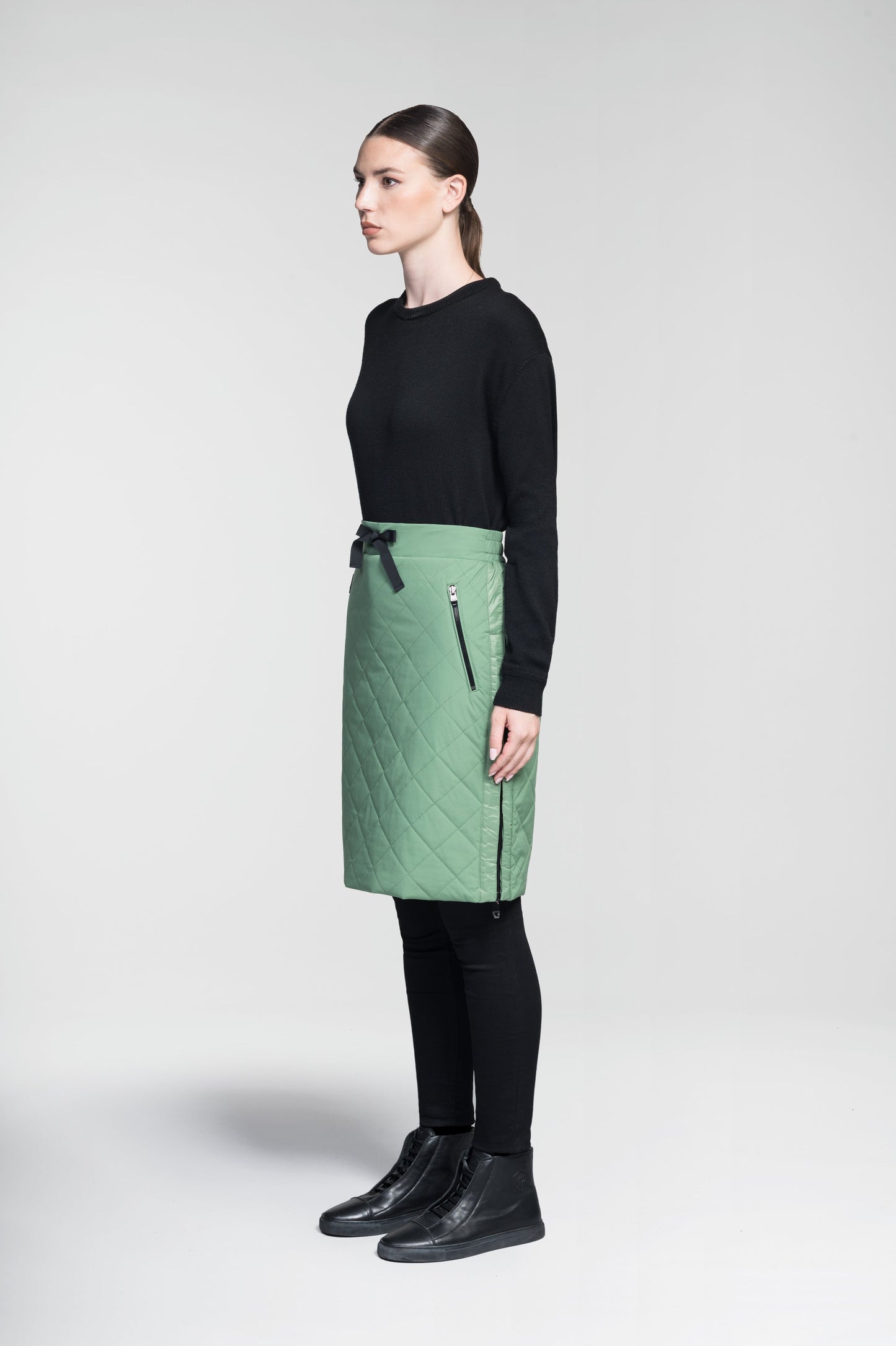 Phora Women's Tailored Skirt in knee length, premium stretch ripstop and contrast cire technical nylon taffeta fabrication, premium 4-way stretch, water resistant Primaloft Gold Insulation Active+, elasticated waistband with grosgrain ribbon drawstrings, two zipper pockets at waist, and zipper closure gusset at side seams, in Comfrey