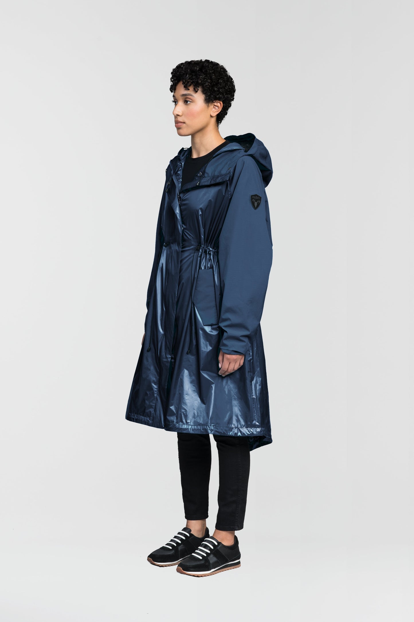 premium strech ripstop and contrast cire technical nylon taffeta fabrication, non-removable hood with adjustable draw cord, waist flap pockets with magnetic closures, adjustable draw cords at waist and bottom hem, adjustable snap cuffs, mesh back ventilation, hidden packable pocket, snap button wind flap, two-way branded zipper at centre front, adjustable snap button fishtail yoke at back, and large interior zipper pocket, in Marine