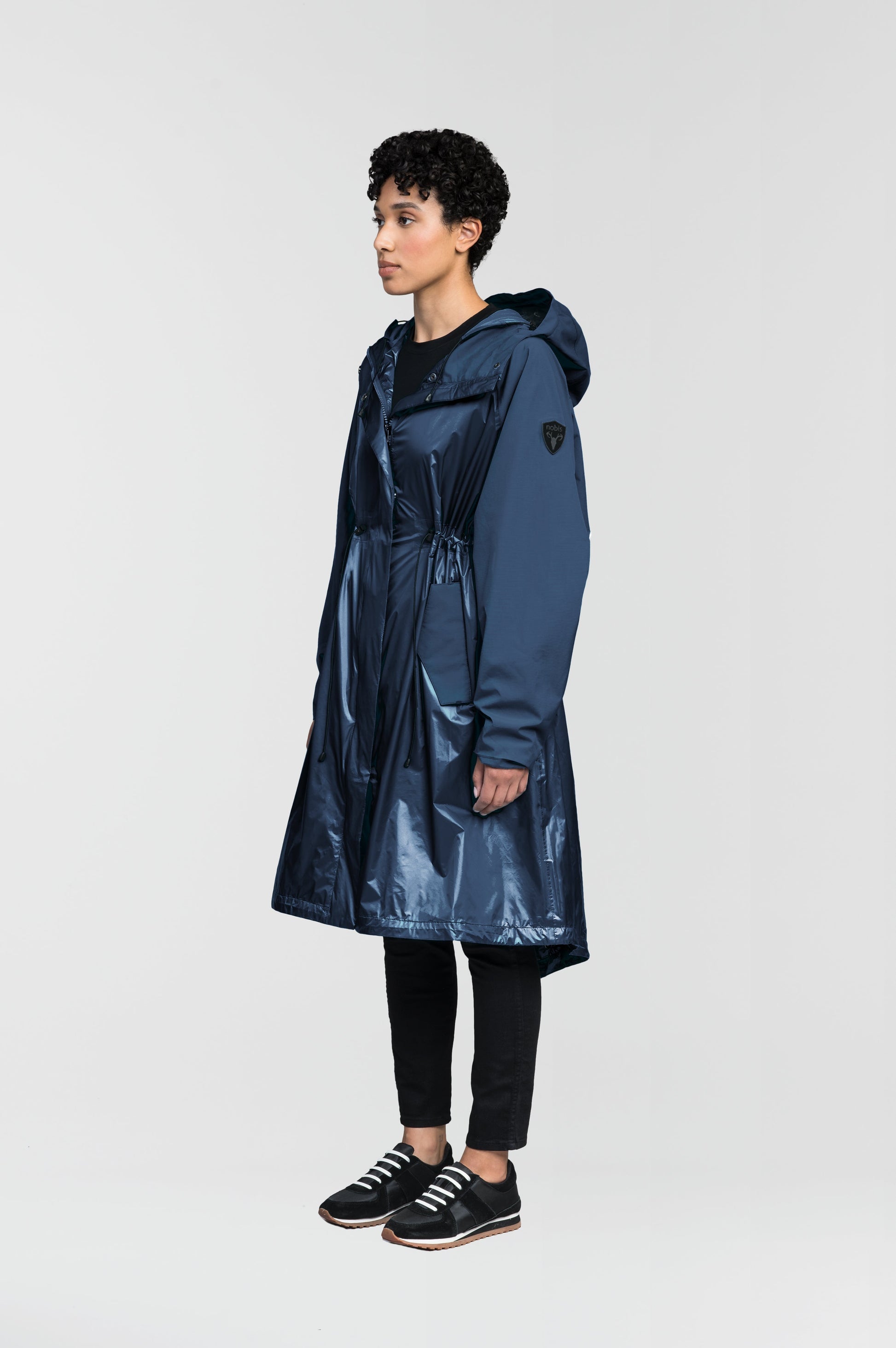 premium strech ripstop and contrast cire technical nylon taffeta fabrication, non-removable hood with adjustable draw cord, waist flap pockets with magnetic closures, adjustable draw cords at waist and bottom hem, adjustable snap cuffs, mesh back ventilation, hidden packable pocket, snap button wind flap, two-way branded zipper at centre front, adjustable snap button fishtail yoke at back, and large interior zipper pocket, in Marine