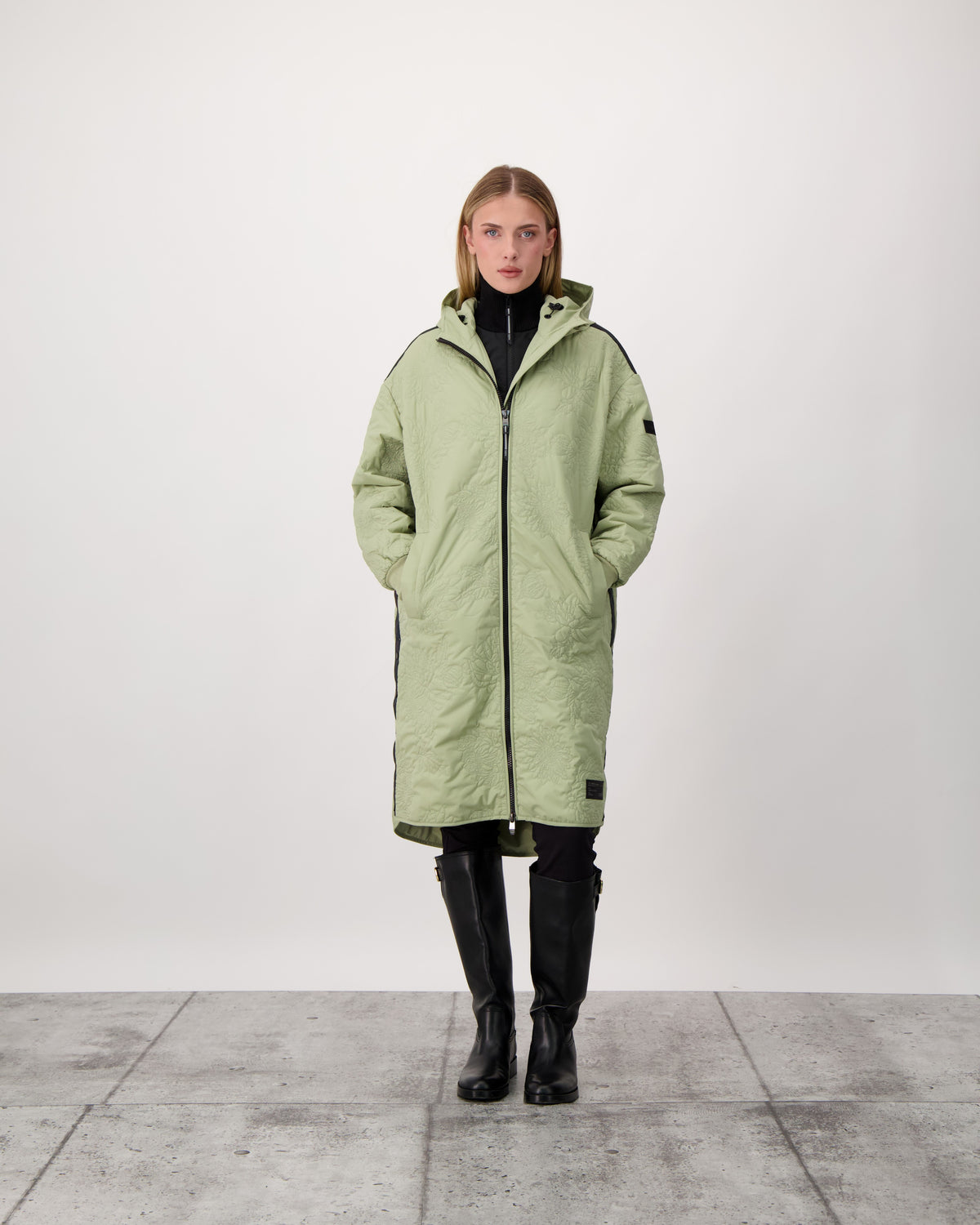 Surrey Women's Performance Quilted Long Mid Layer Jacket in knee length, Primaloft Gold Insulation Active+, non-removable hood, single welt magnetic closure pockets, ribbed cuffs, two-way centre front zipper, grosgrain ribbon detail and shoulders and side seam, and snap closure side seam vents, in Tea