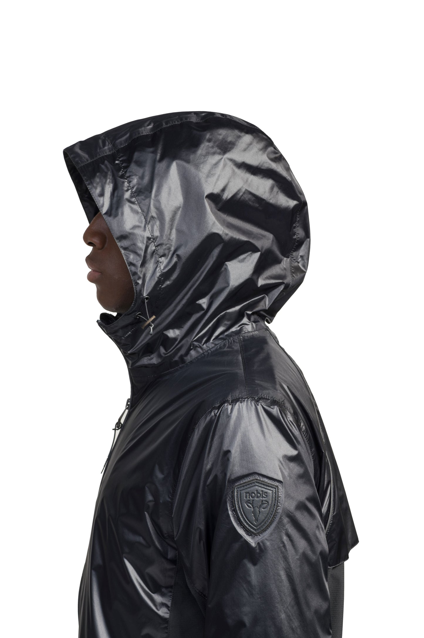 Stratus Men's Tailored Packable Rain Jacket in hip length, premium cire technical nylon taffeta and stretch ripstop fabrication, highly breathable mesh lining, hidden packable pocket, non-removable hood with adjustable draw cord, reflective piping along front and back, underarm grommets for extra breathability, back yoke with mesh ventilation, two waist zipper pockets, two interior zipper pockets, elastic cuffs with adjustable snap button, and adjustable interior draw cord at waist hem, in Black