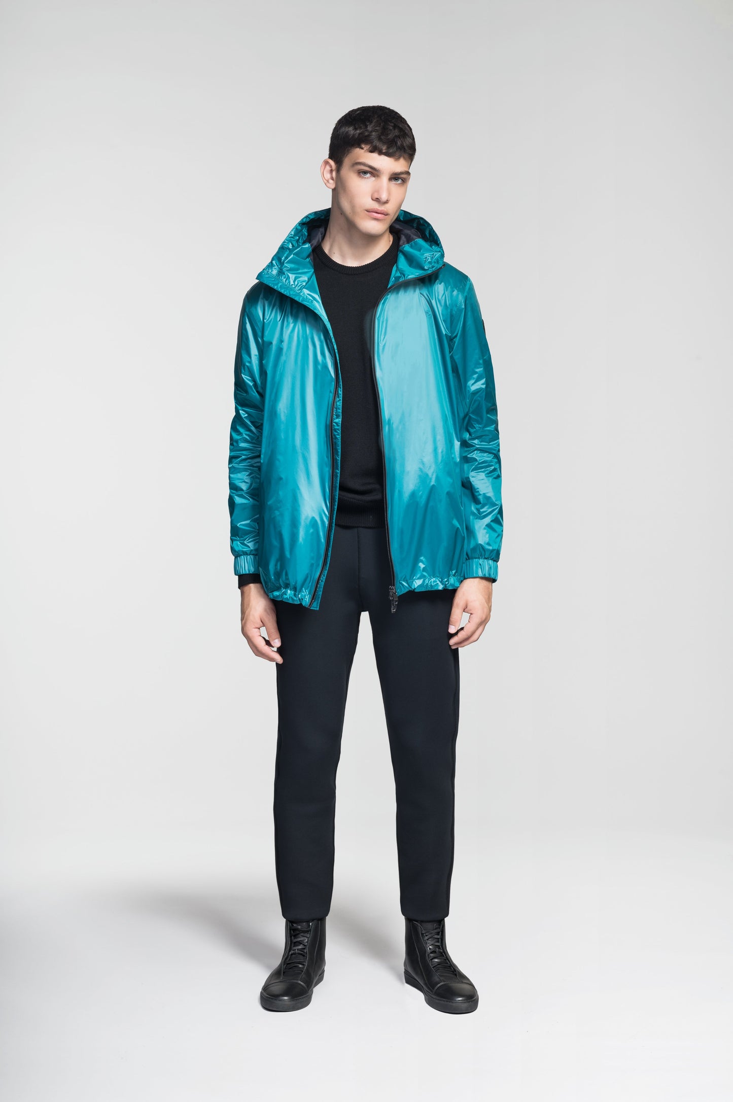 Stratus Men's Tailored Packable Rain Jacket in hip length, premium cire technical nylon taffeta and stretch ripstop fabrication, highly breathable mesh lining, hidden packable pocket, non-removable hood with adjustable draw cord, reflective piping along front and back, underarm grommets for extra breathability, back yoke with mesh ventilation, two waist zipper pockets, two interior zipper pockets, elastic cuffs with adjustable snap button, and adjustable interior draw cord at waist hem, in Deep Lake