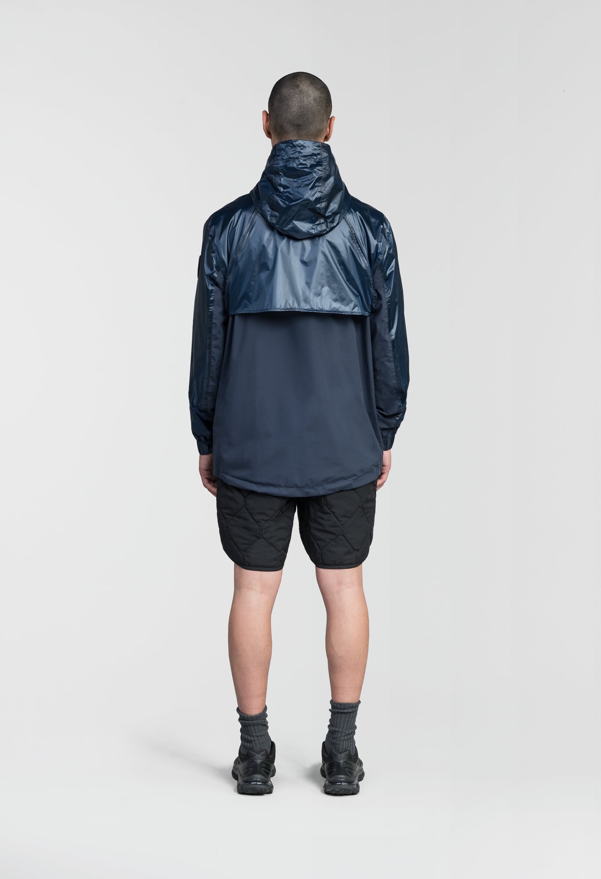 Stratus Men's Tailored Packable Rain Jacket in hip length, premium cire technical nylon taffeta and stretch ripstop fabrication, highly breathable mesh lining, hidden packable pocket, non-removable hood with adjustable draw cord, reflective piping along front and back, underarm grommets for extra breathability, back yoke with mesh ventilation, two waist zipper pockets, two interior zipper pockets, elastic cuffs with adjustable snap button, and adjustable interior draw cord at waist hem, in Marine