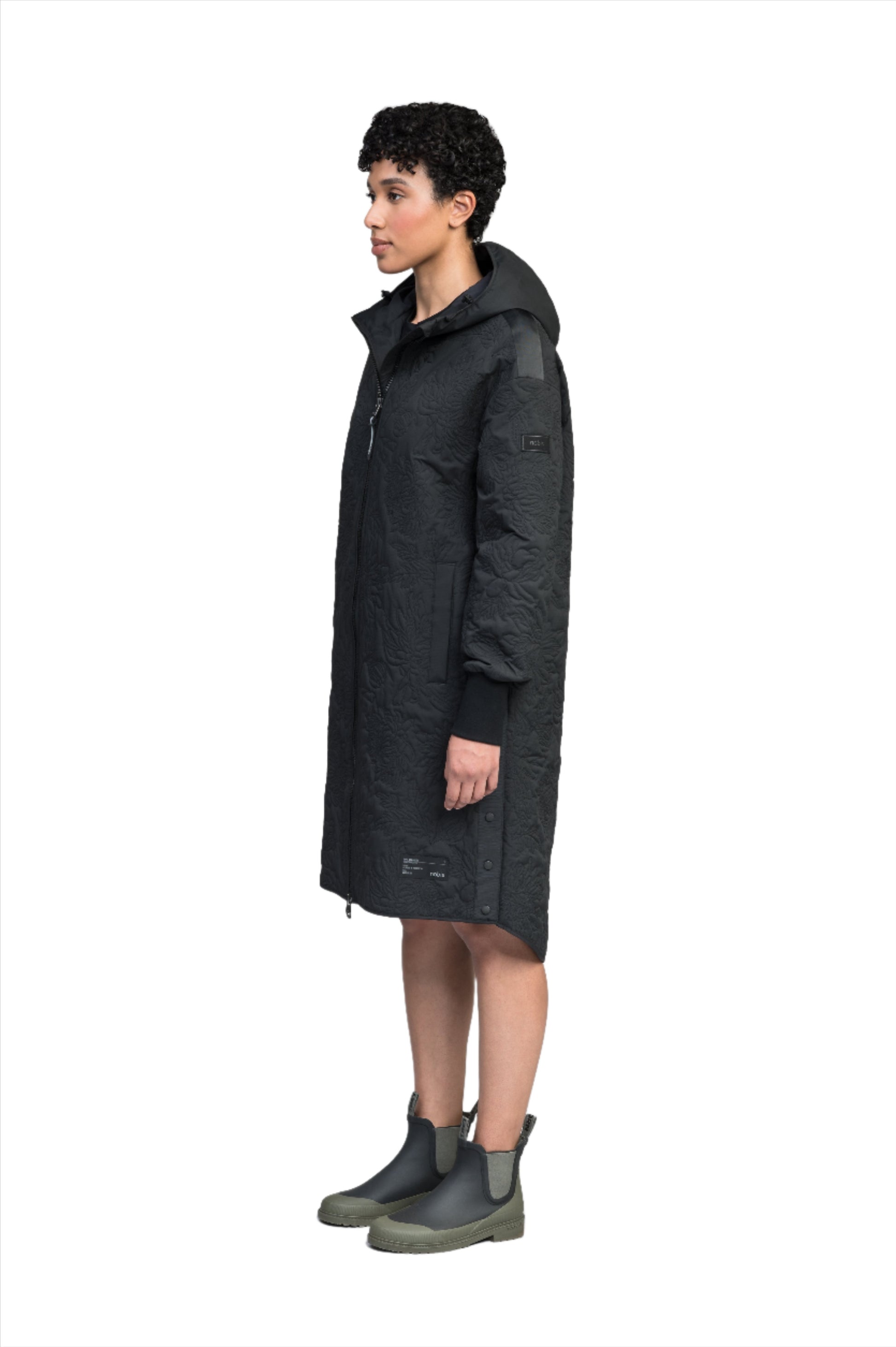 Surrey Women's Performance Quilted Long Mid Layer Jacket in knee length, Primaloft Gold Insulation Active+, non-removable hood, single welt magnetic closure pockets, ribbed cuffs, two-way centre front zipper, grosgrain ribbon detail and shoulders and side seam, and snap closure side seam vents, in Black