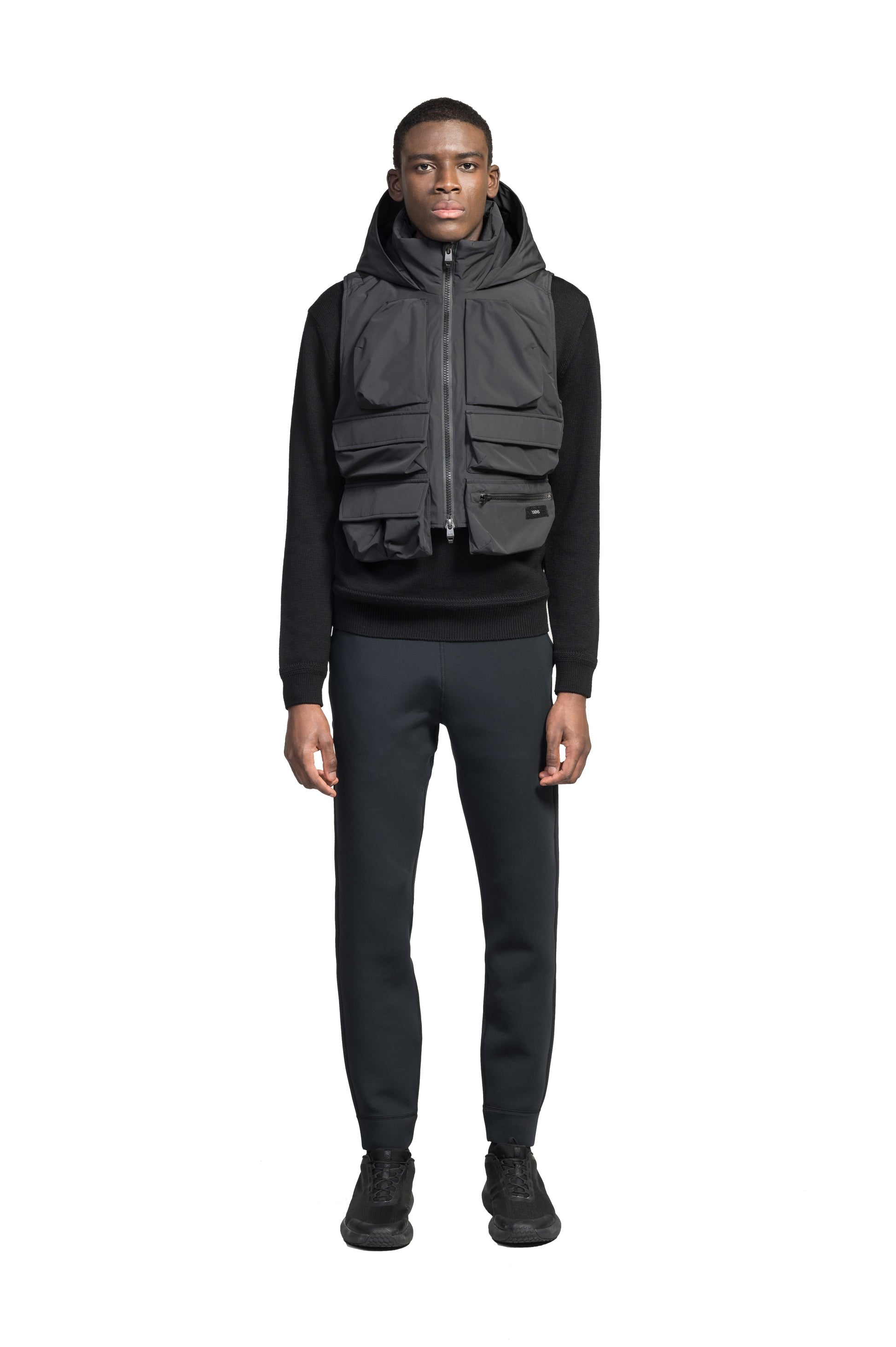 Vulcan Unisex Tactical Vest in waist length, Primaloft Gold Insulation Active, non-removable hood, removable face mask, seven pockets on front and back, and two-way front zipper, in Black