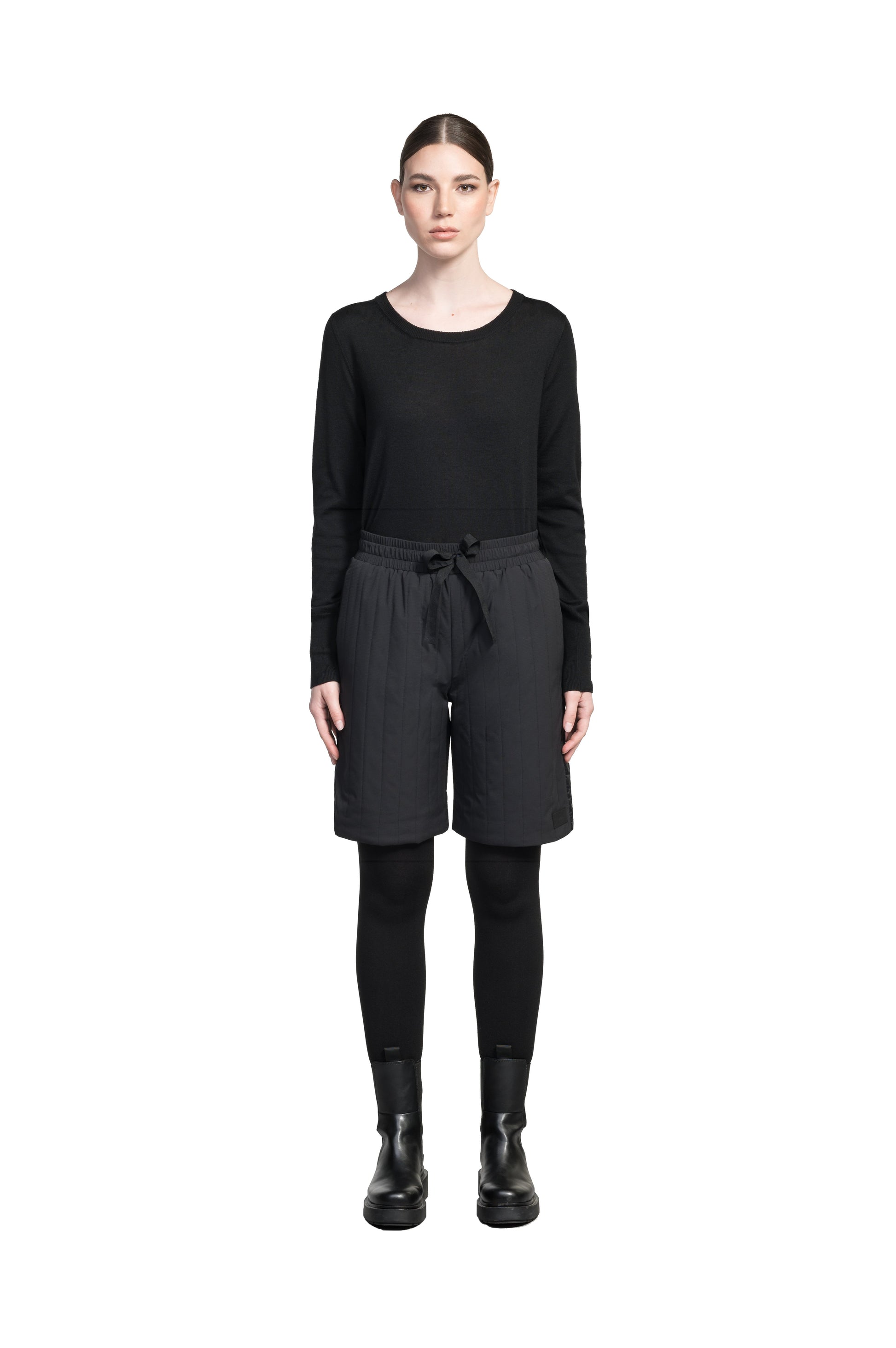 Kit Women's Quilted Shorts in knee length, premium stretch ripstop and contrast cire technical nylon taffeta fabrication, premium 4-way stretch, water resistant Primaloft Gold Insulation Active+, elasticized waistband with grosgrain ribbon drawstrings, hidden side seam toggles for rouching detail, snap closure side seam pockets at hips, and single welt snap button pockets at back, in Black