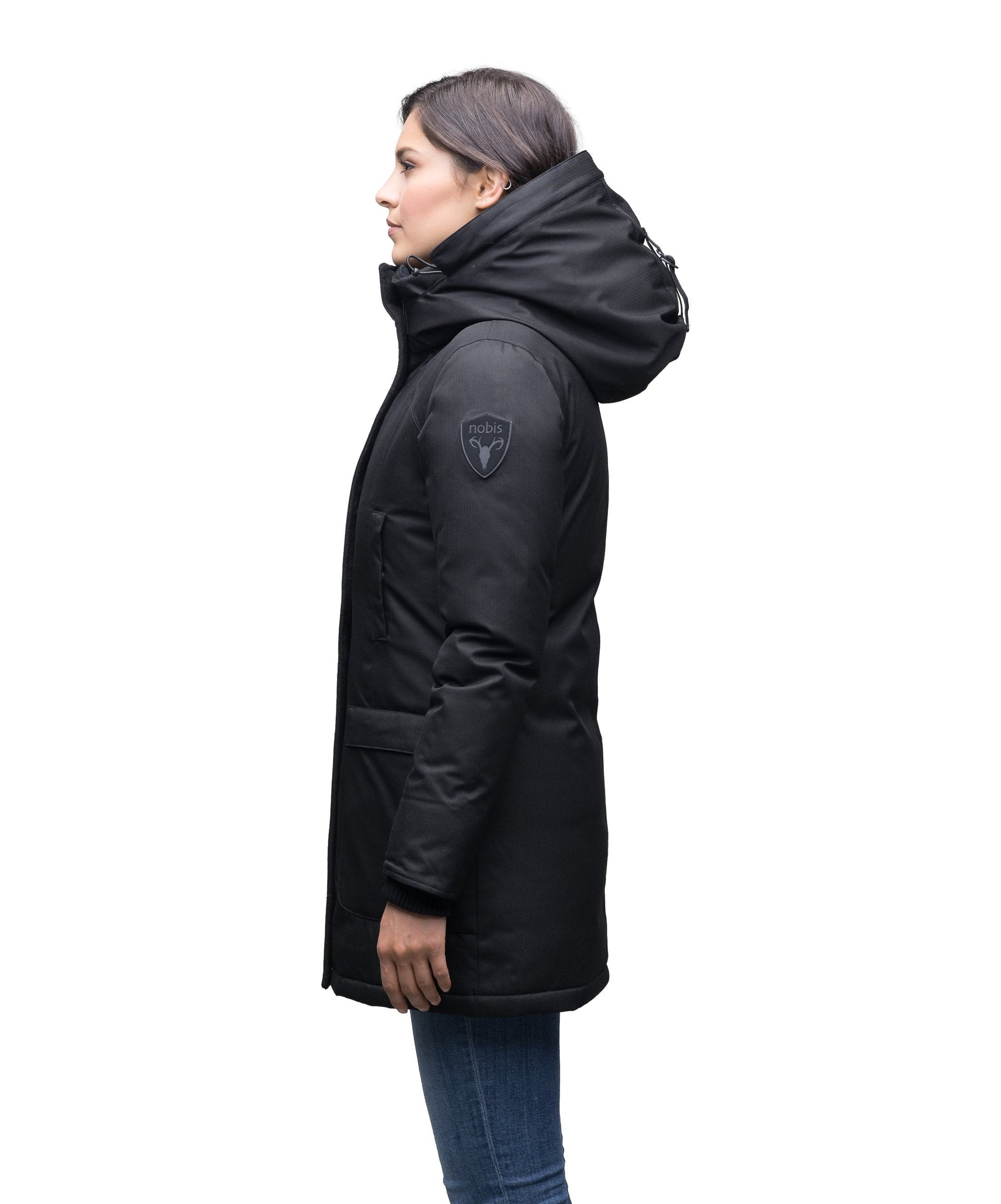 Women's down filled parka that sits just below the hip with a clean look and two hip patch pockets in BlackCarla Furless Ladies Parka in thigh length with Canadian Premium White Duck Down insulation, non-removable hood, centre-front zipper with magnetic closure wind flap, and four exterior pockets, in Black