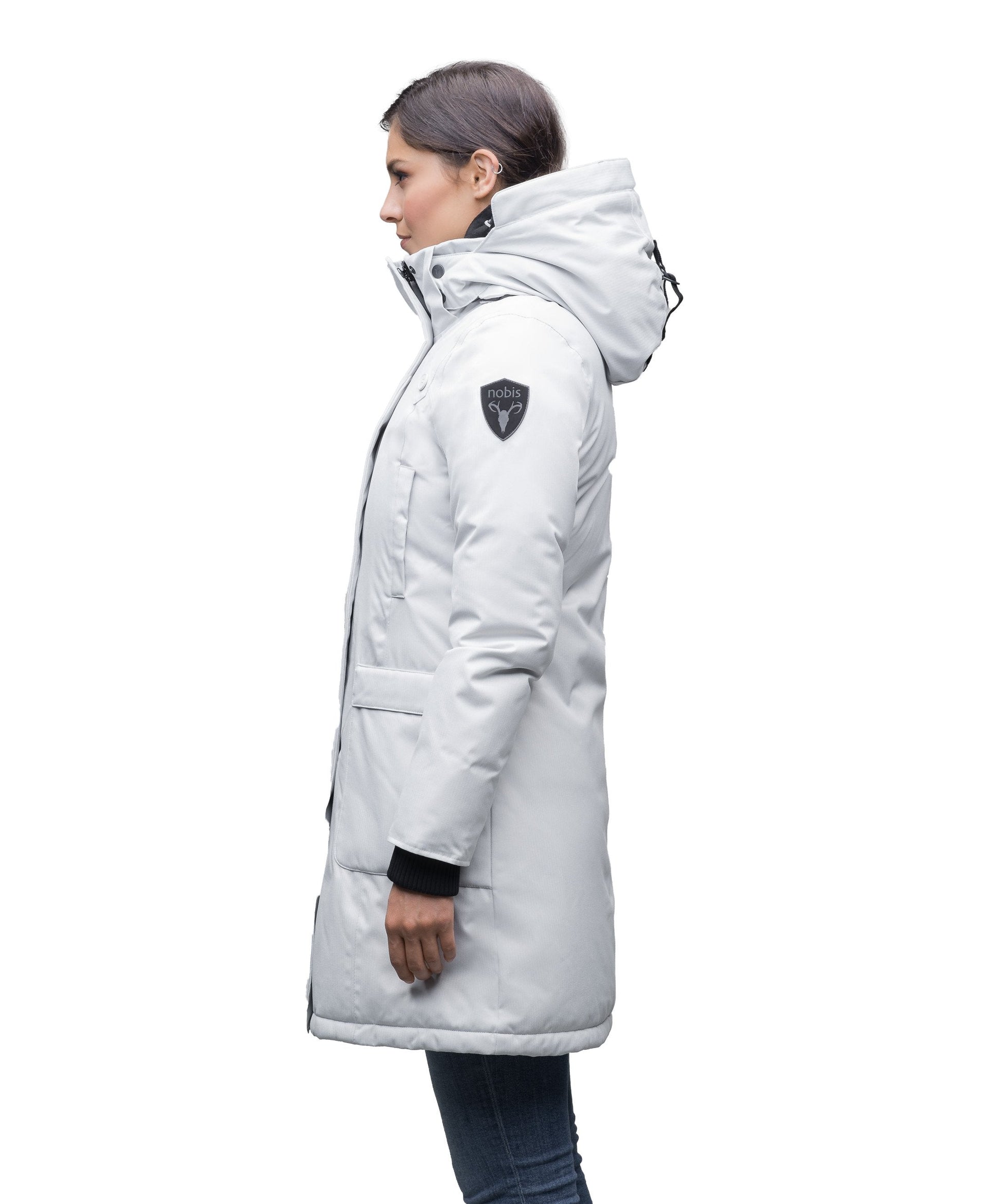 Merideth Furless Ladies Parka in thigh length, Canadian white duck down insulation, removable down-filled hood, centre-front two-way zipper with magnetic wind flap closure, four exterior pockets, and elastic ribbed cuffs, in Light Grey